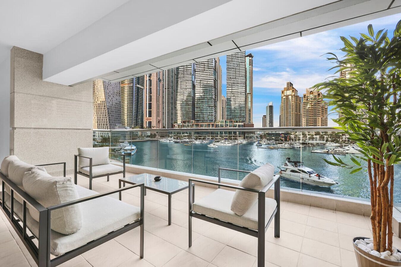 A balcony with a city view, modern furniture, and a potted plant.