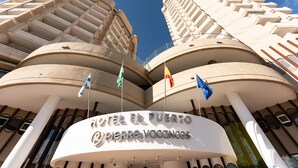 Un hotel con fachada curva, varios balcones y banderas.