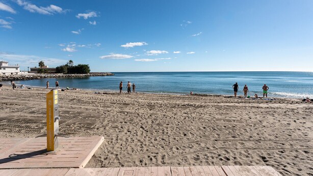 Una playa con una terraza de madera y un letrero amarillo.