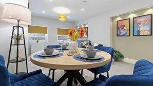 Un comedor moderno con una mesa redonda, sillas tapizadas en azul y una lámpara de pie.