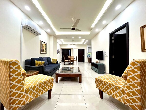 A modern living room with a sofa, armchairs, a coffee table, and a TV.