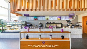L'intérieur d'un café moderne, avec un plafond en bois, un comptoir sur lequel est affiché le menu et une vitrine présentant différentes tasses à café.