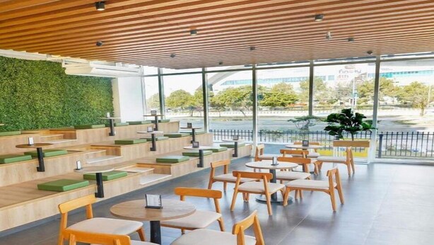 Un café moderne avec des niveaux d’assises et de grandes fenêtres donnant sur la rue.