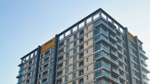 Un immeuble à étages doté d’une architecture moderne, caractérisé par une enseigne jaune bien visible et une façade aux motifs géométriques.