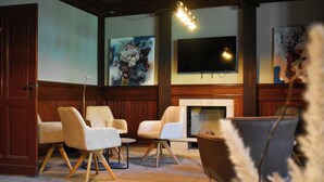 A room with a fireplace, two sofas, and a television mounted on the wall.