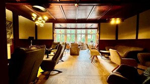 A spacious interior with wooden flooring, multiple seating areas, and large windows allowing natural light.