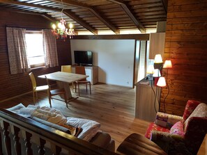 A cozy room with a wooden ceiling, a dining table with chairs, a TV, and a sofa. - Pretty Apartment for Nature Lovers (Bad Kleinkirchheim)