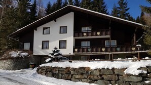 A multi-story wooden building with balconies, surrounded by snow and trees. - Pretty Apartment for Nature Lovers (Bad Kleinkirchheim)