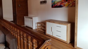 A wooden staircase, a radiator, a cabinet, and a colorful abstract painting on the wall. - Pretty Apartment for Nature Lovers (Bad Kleinkirchheim)