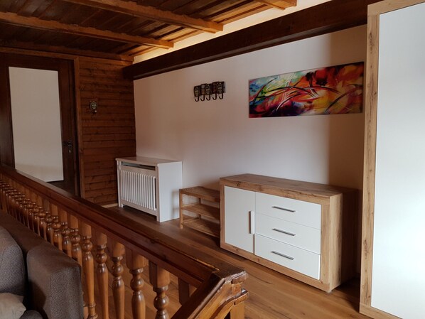 A wooden staircase, a radiator, a cabinet, and a colorful abstract painting on the wall. - Pretty Apartment for Nature Lovers (Bad Kleinkirchheim)