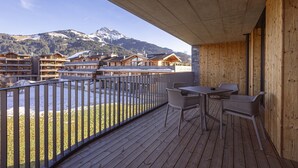 A wooden deck with outdoor seating, overlooking a mountainous landscape and a ski resort.