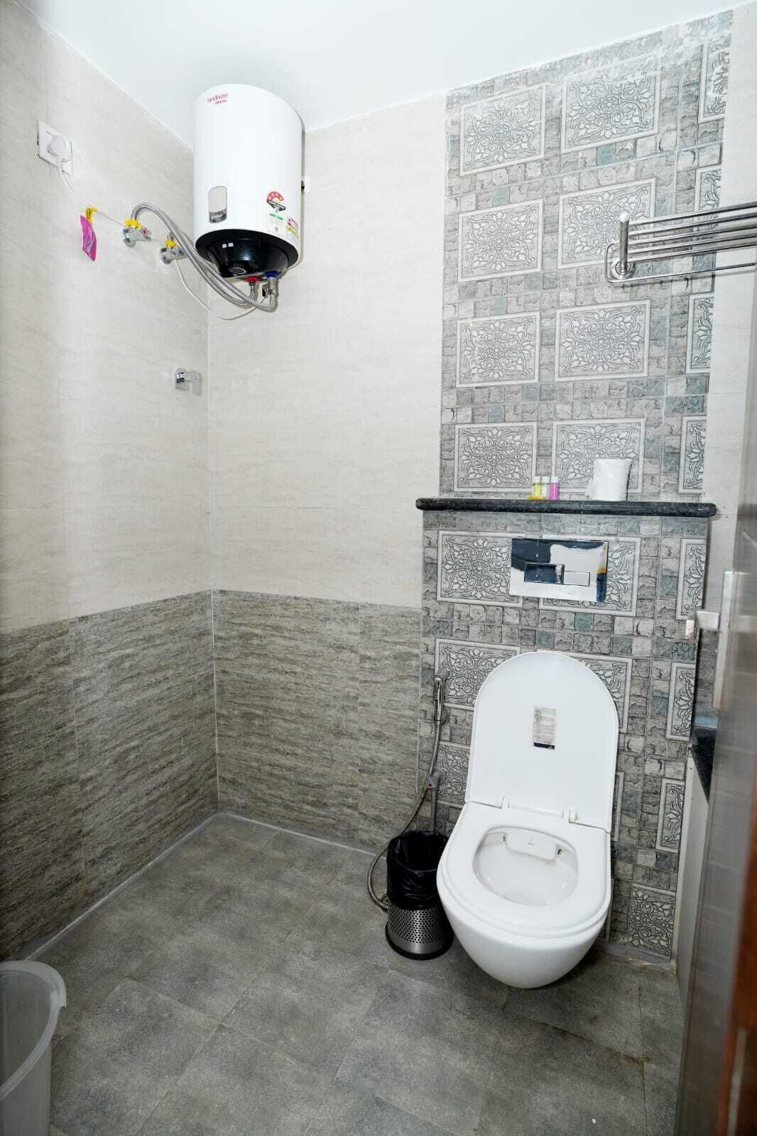 A small bathroom with a toilet, a shower, and a wall-mounted heater.