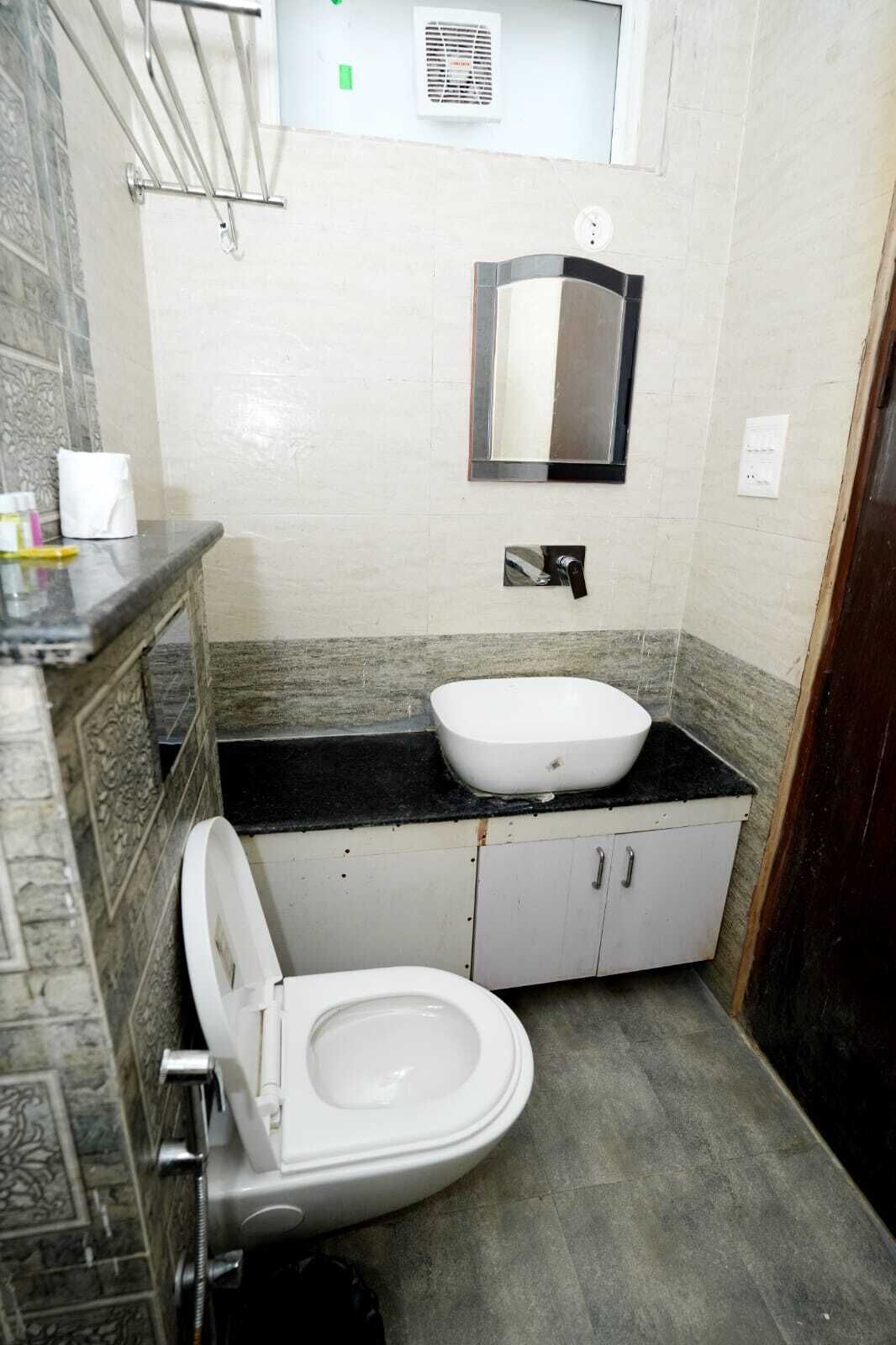 A bathroom with a white toilet, a sink, and a mirror on the wall.