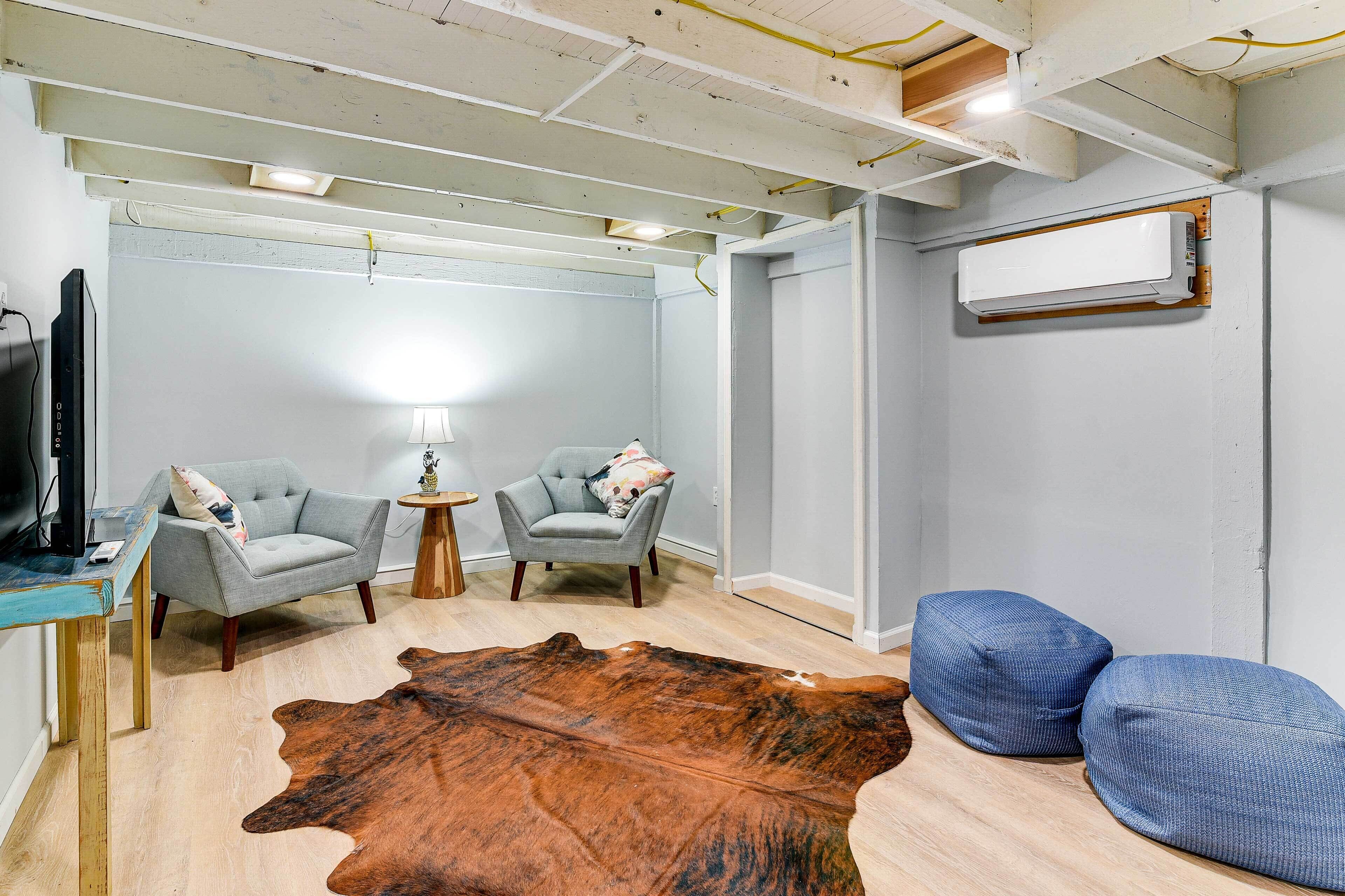 A room with two grey armchairs, a wooden coffee table, a large leather rug, and a blue bean bag.