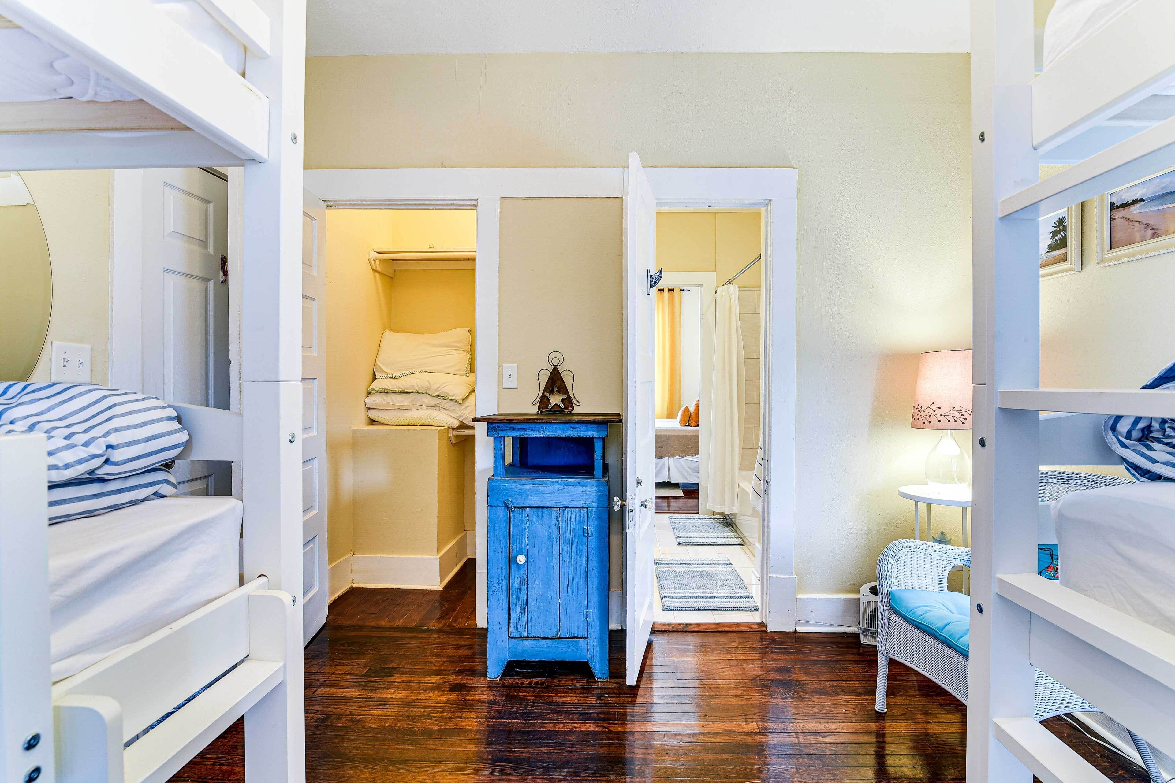 A room with bunk beds, a small blue cabinet, and a wicker chair.