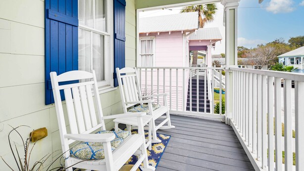 A porch with white rocking chairs and a blue and yellow patterned rug. - Walk to Beach! Family-friendly Galveston Home (Galveston)