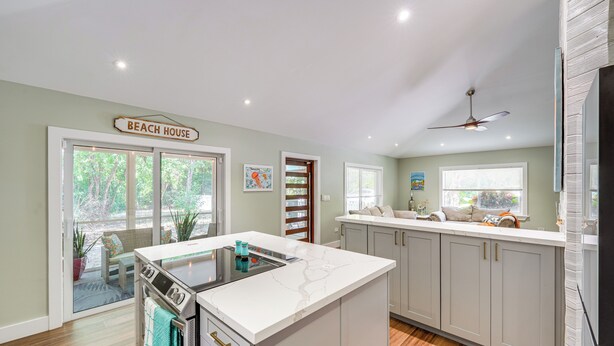 A modern kitchen with a central island, white cabinetry, and a ceiling fan. - Walk to Harry Harris Beach: Modern Coastal Escape! (Tavernier)
