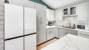 A modern kitchen with white cabinets, a built-in microwave, and a coffee maker. - Walk to Harry Harris Beach: Modern Coastal Escape! (Tavernier)