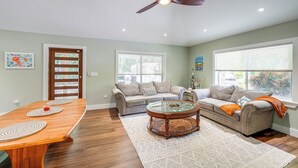 A living room with a wooden dining table, two sofas, a glass coffee table, and a ceiling fan. - Walk to Harry Harris Beach: Modern Coastal Escape! (Tavernier)