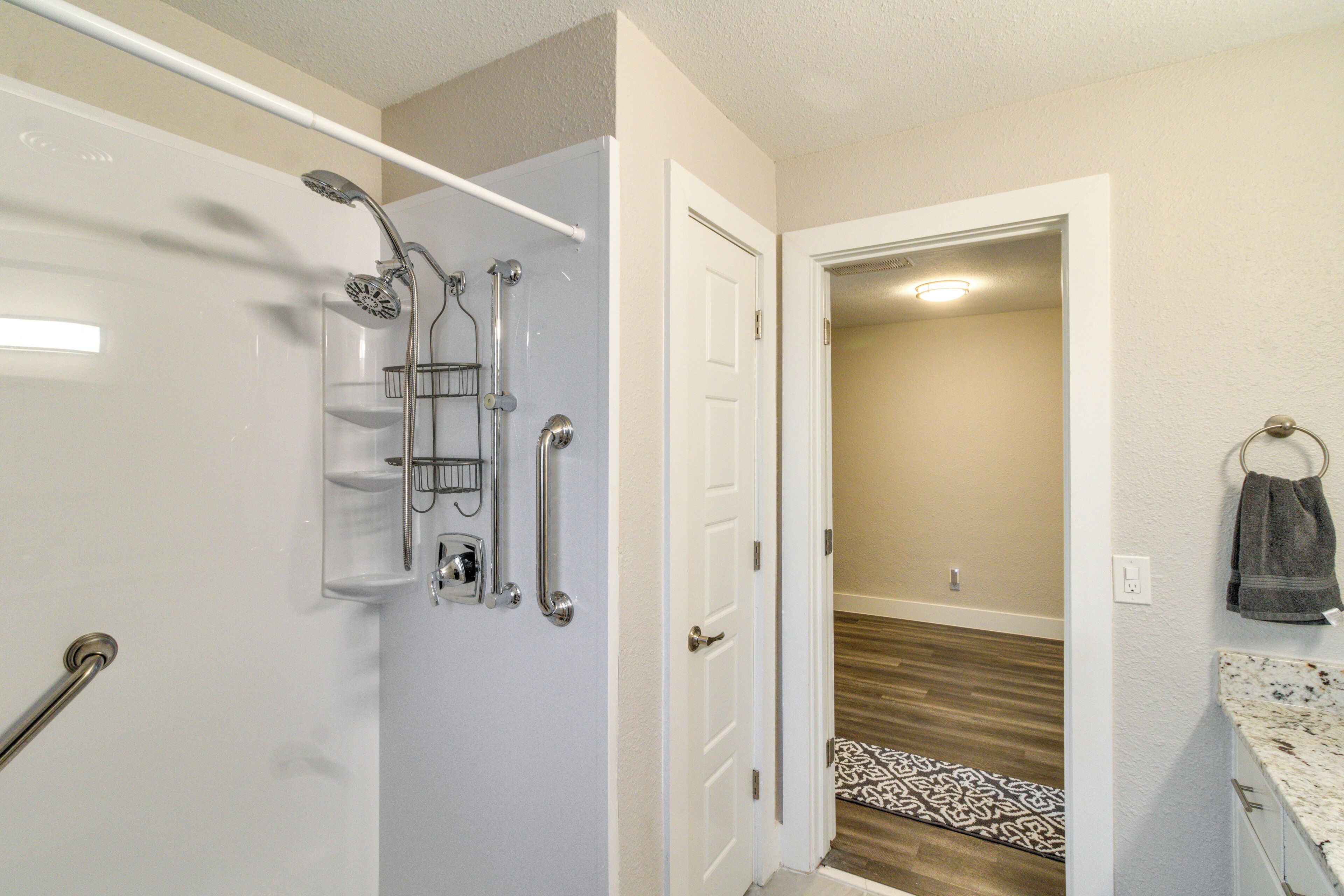 A bathroom with a shower, a towel rack, and a door leading to a hallway.