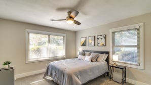 A bedroom with a bed, ceiling fan, bedside table, lamp, and window blinds. - Home w/ Patio & Games Near Dtwn Pensacola! (Pensacola)