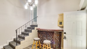 A staircase with a handrail, a white door, and two wooden stools. - Home w/ Patio & Games Near Dtwn Pensacola! (Pensacola)