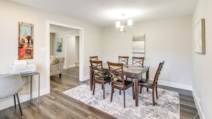 A dining area with a table and chairs, a rug, and artwork on the walls. - Home w/ Patio & Games Near Dtwn Pensacola! (Pensacola)