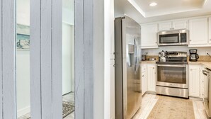 A modern kitchen with stainless steel appliances, white cabinetry, and a patterned floor. - Waterfront Condo w/ Dock Access in Carlsbad! (Carlsbad)
