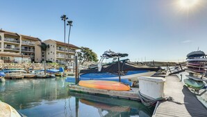 A marina with boats docked, a wooden pier, and a multi-story building with balconies. - Waterfront Condo w/ Dock Access in Carlsbad! (Carlsbad)
