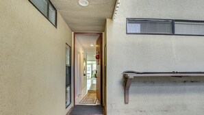 A narrow hallway with a tiled floor leading to a door, a small step, and a pair of shoes on a mat. - Waterfront Condo w/ Dock Access in Carlsbad! (Carlsbad)