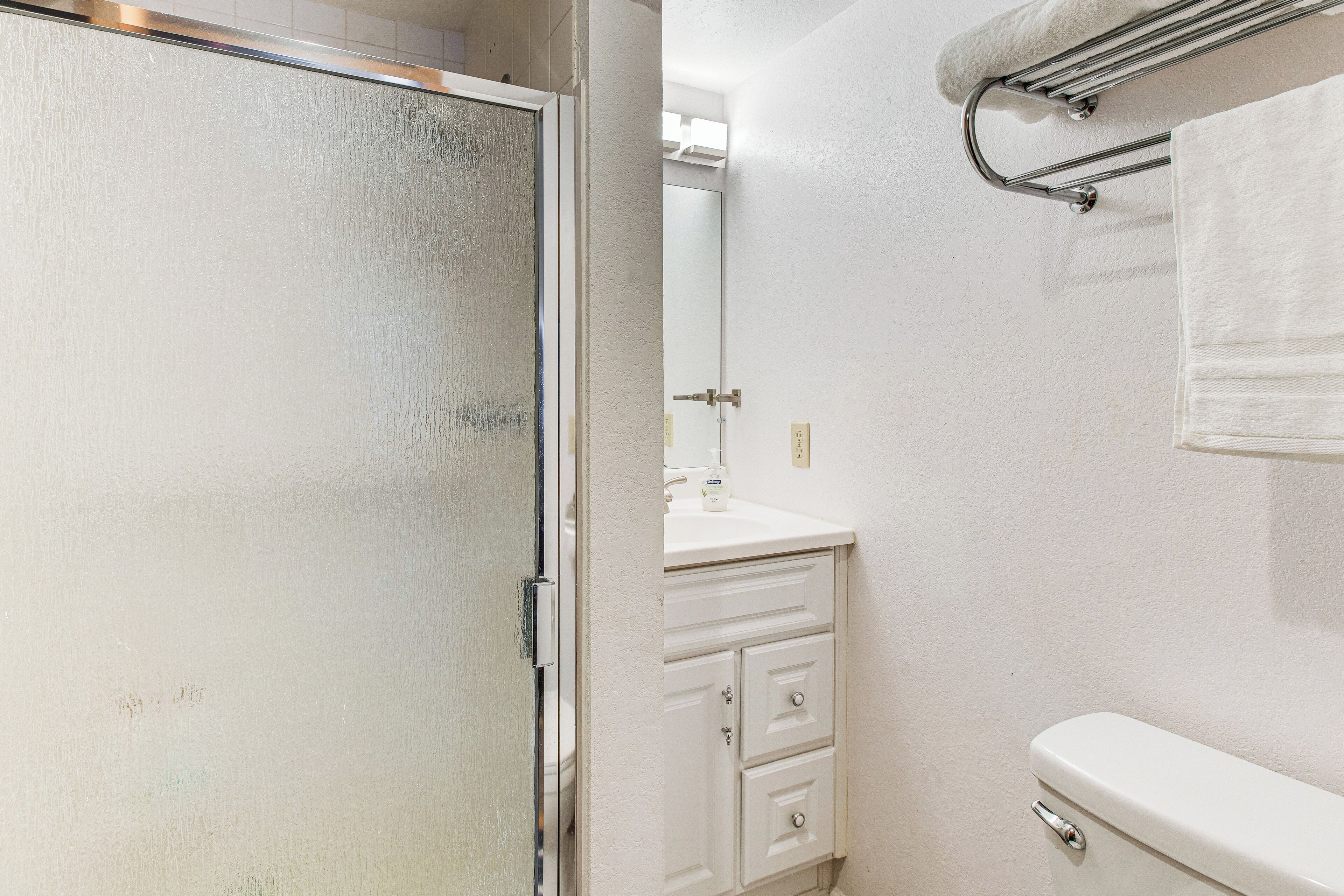 A bathroom with a white toilet, a sink with a mirror above it, and a towel rack with a towel.