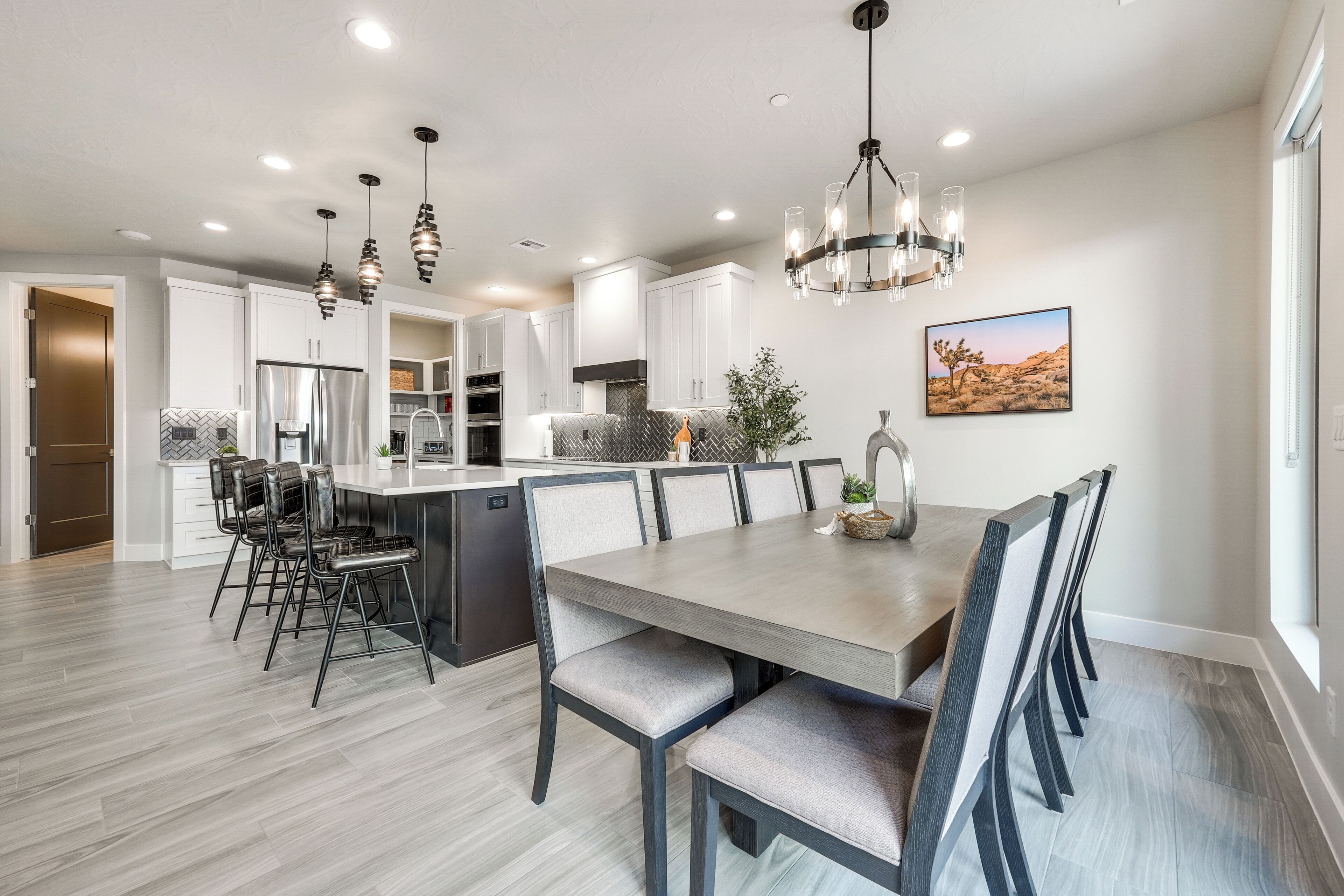 A modern kitchen with white cabinets, a central island, and a dining area with a large table and chairs.