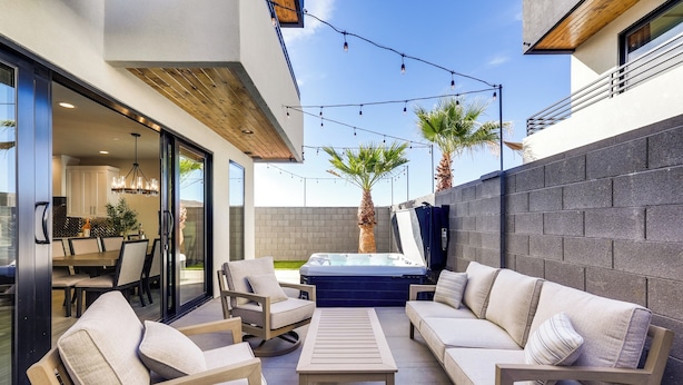 Une terrasse extérieure avec un canapé, des fauteuils, une table et un jacuzzi.