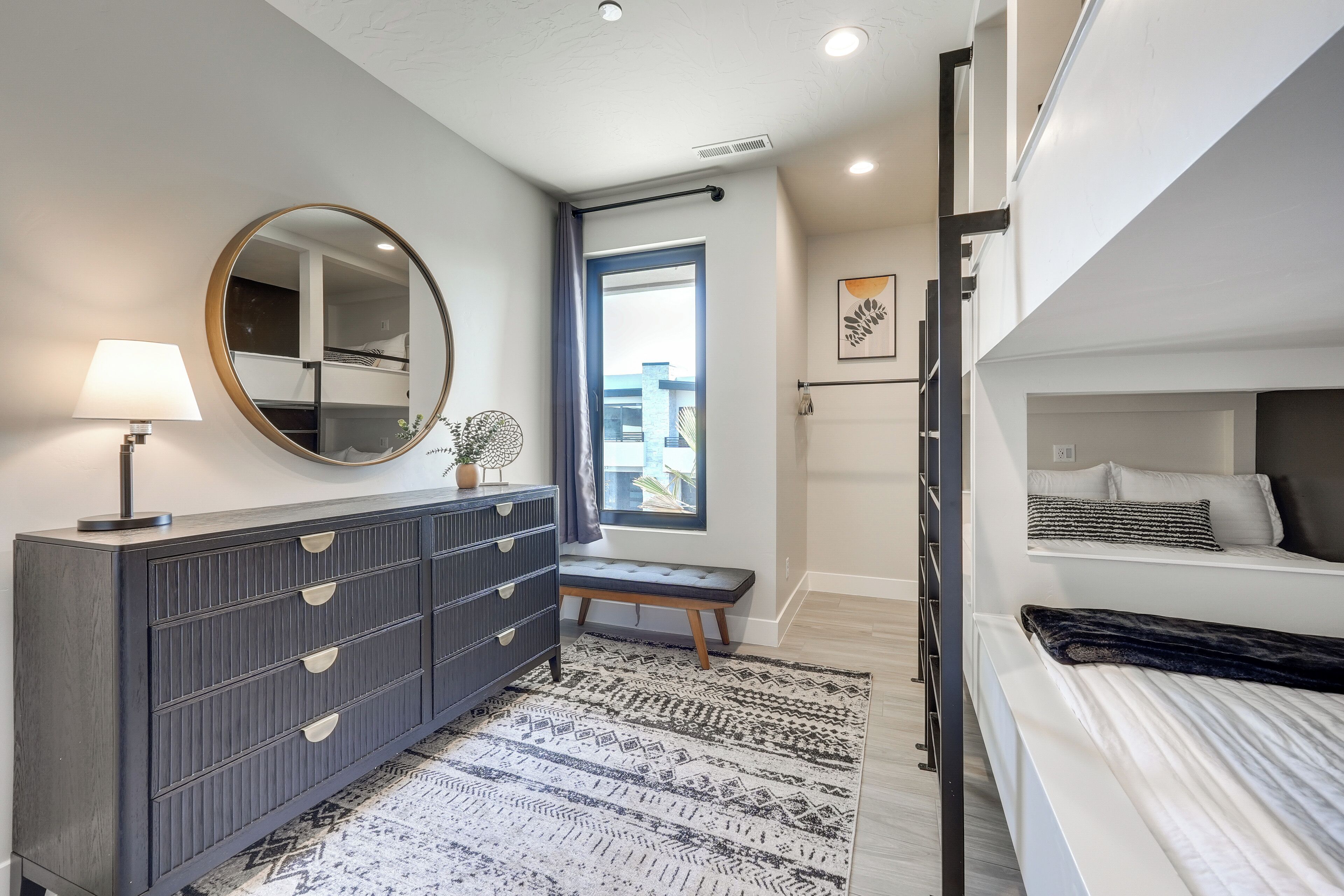 A modern bedroom with a bed, a dresser, a mirror, and a bench.