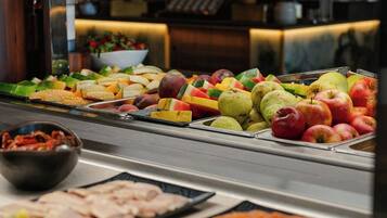 Un bufé con diversas frutas y un tazón de verduras encurtidas.