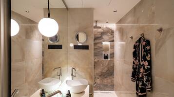 A modern bathroom with two sinks, a large mirror, and a robe hanging on the wall.