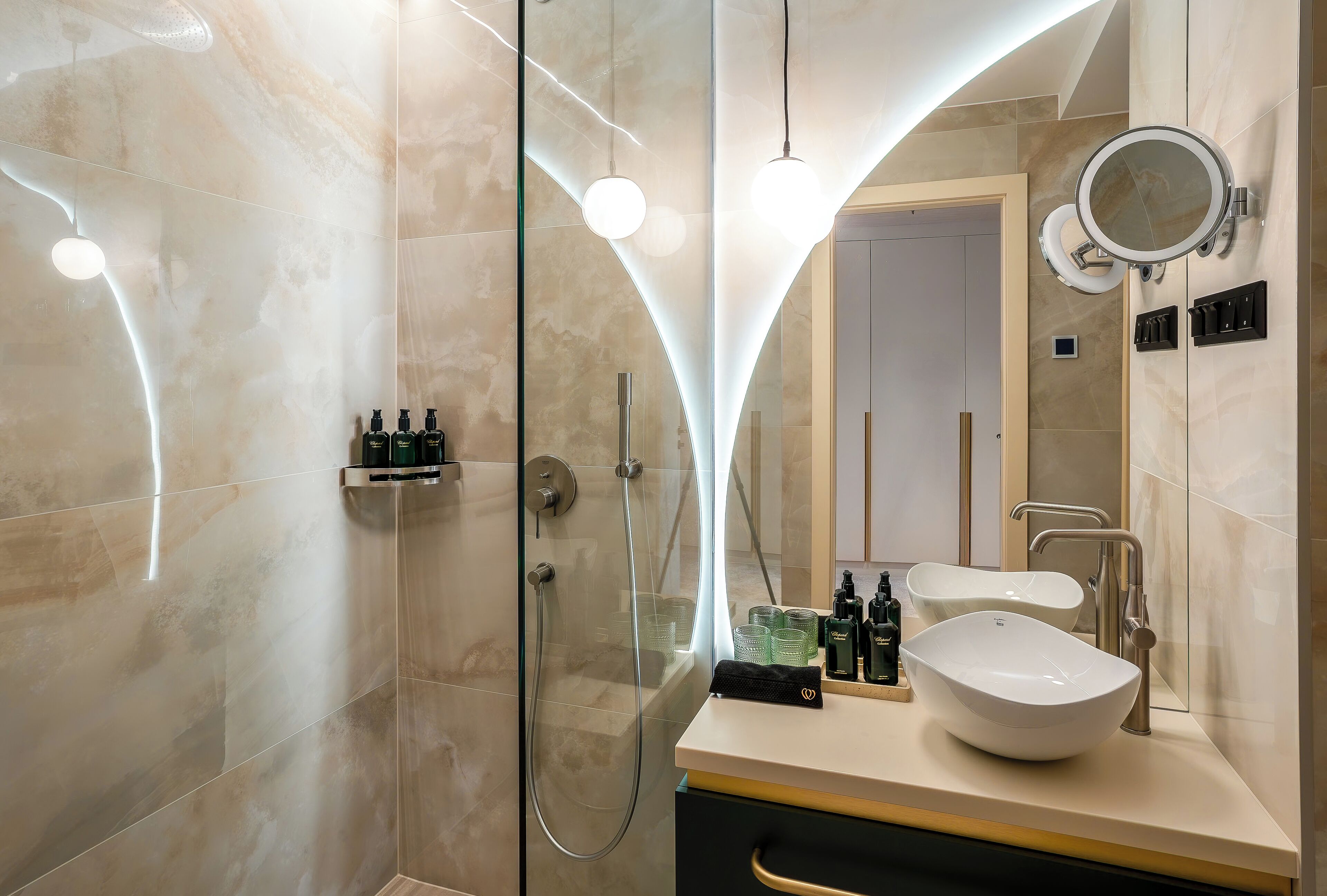 A modern bathroom with a glass-enclosed shower, a vanity with a large mirror, and a sink.