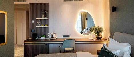 Una habitación de hotel moderna con una cama, un escritorio, una silla, un espejo y una planta.