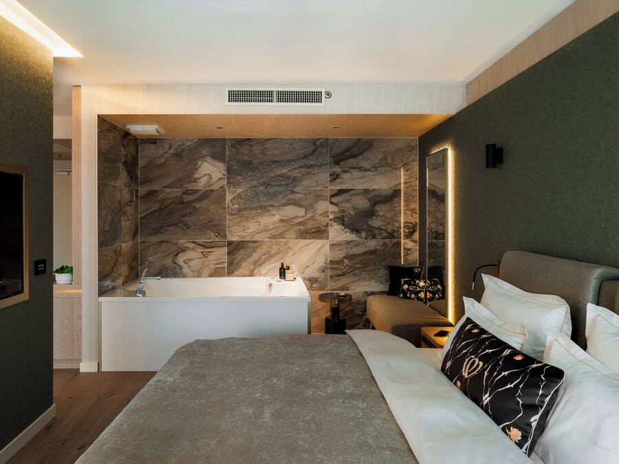 A modern bedroom with a large bed, a built-in bathtub, and a large mirror.