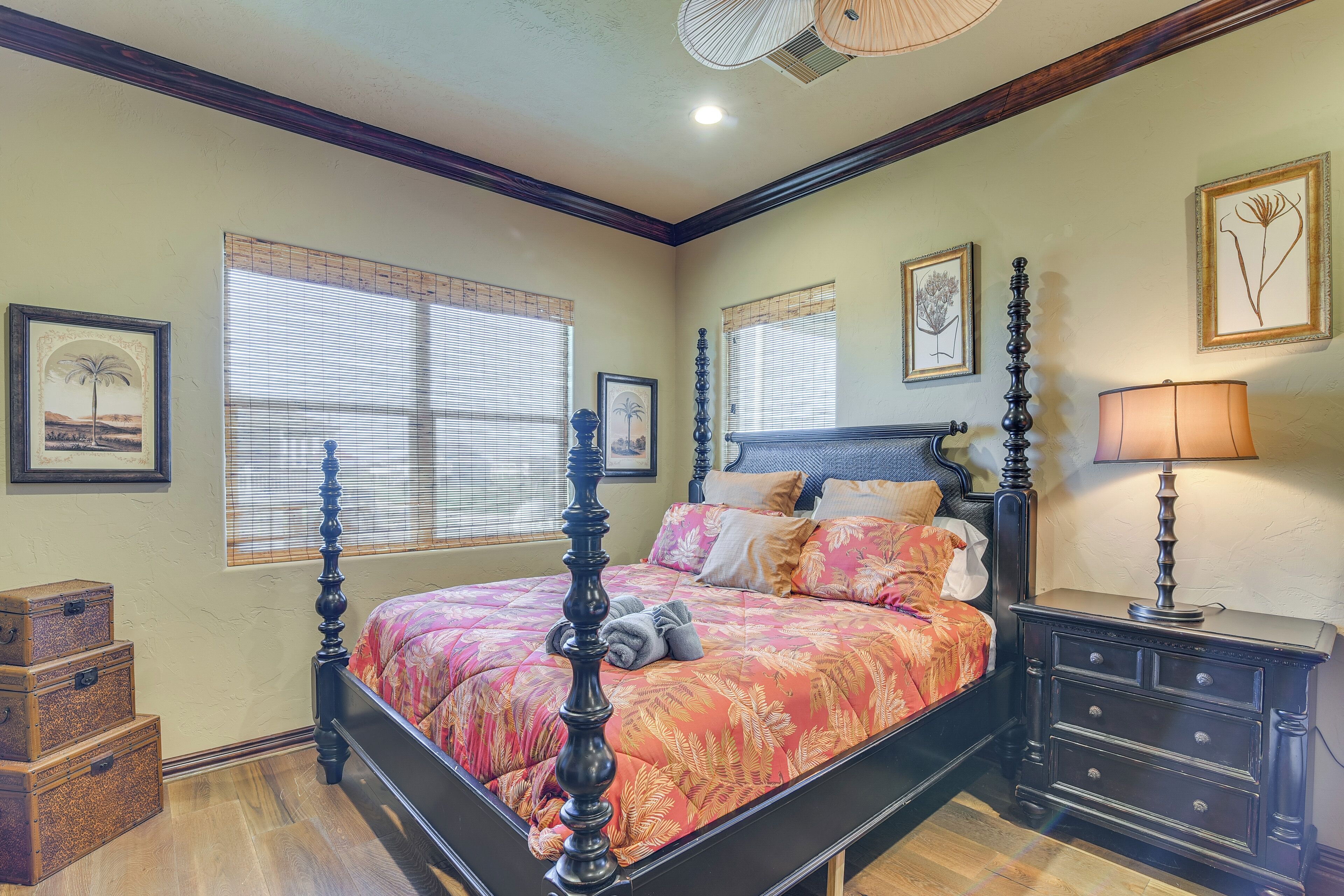 A bedroom with a four-poster bed, a nightstand with a lamp, and framed botanical artwork on the walls.