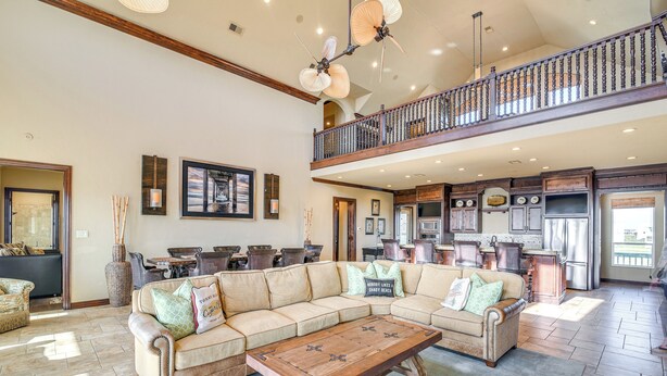 A spacious living room with a large sectional sofa, a wooden coffee table, and a dining area with chairs. - Beachfront Group Getaway on Bolivar Peninsula (Port Bolivar)