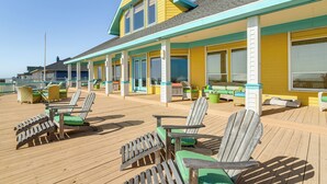 A wooden deck with several Adirondack chairs and a covered seating area with tables and chairs. - Beachfront Group Getaway on Bolivar Peninsula (Port Bolivar)