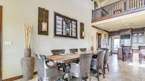A spacious dining area with a high ceiling, a large framed picture, and a view to the upper level. - Beachfront Group Getaway on Bolivar Peninsula (Port Bolivar)