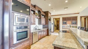 A kitchen with stainless steel appliances, wooden cabinets, and a granite countertop. - Beachfront Group Getaway on Bolivar Peninsula (Port Bolivar)