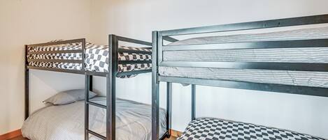 Ein Schlafsaalzimmer mit Etagenbetten, Holzboden und schlichten Wänden.