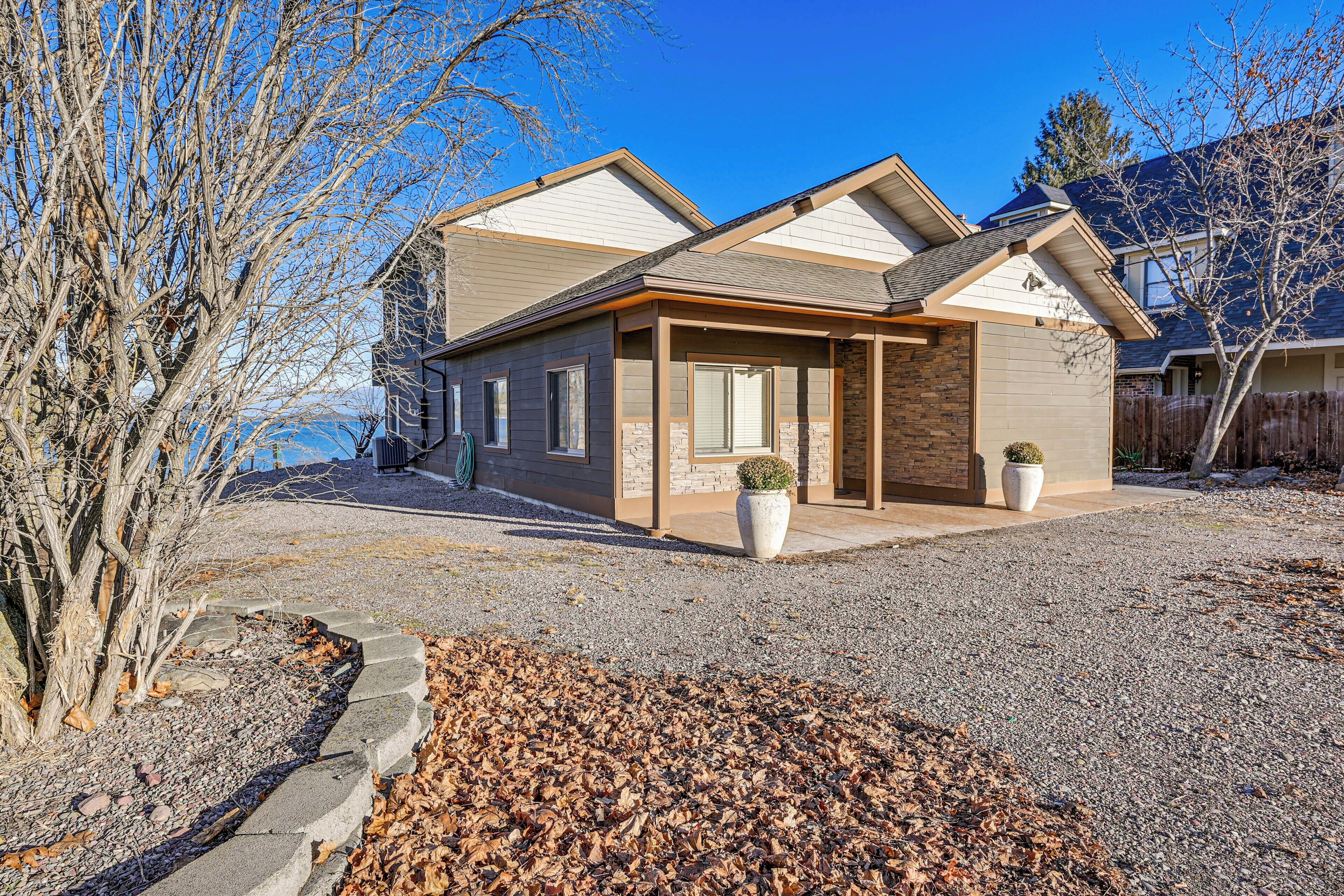 A modern two-story house with a covered porch, stone accents, and a gravel driveway.