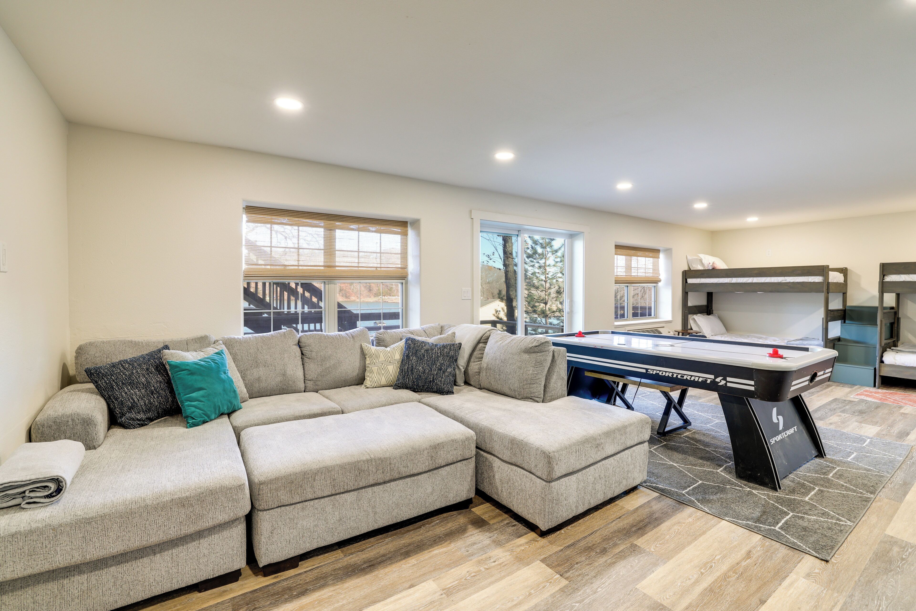 A spacious living room with a sectional sofa, a foosball table, and large windows providing natural light.