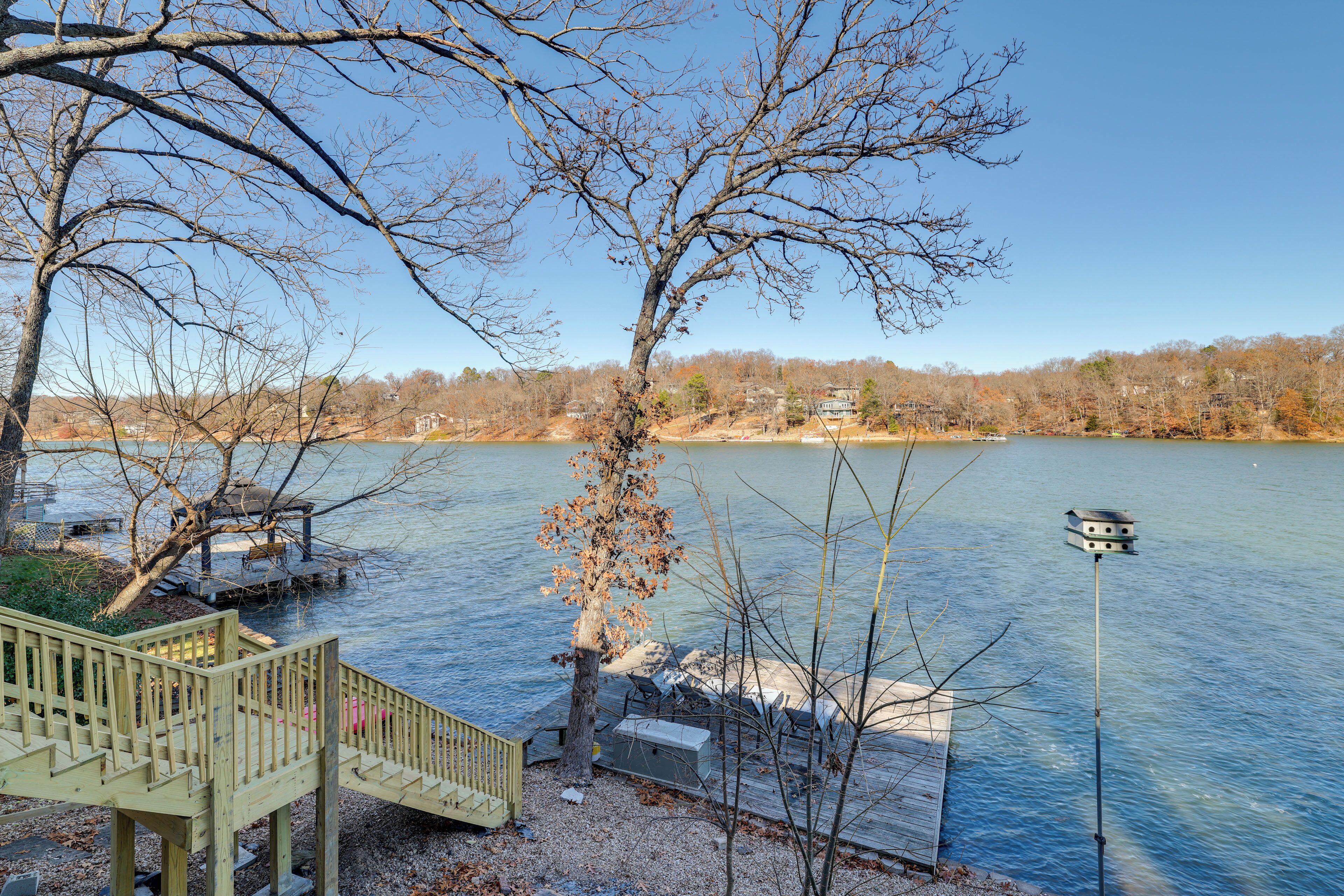 A wooden dock extending into a calm lake with a clear sky.