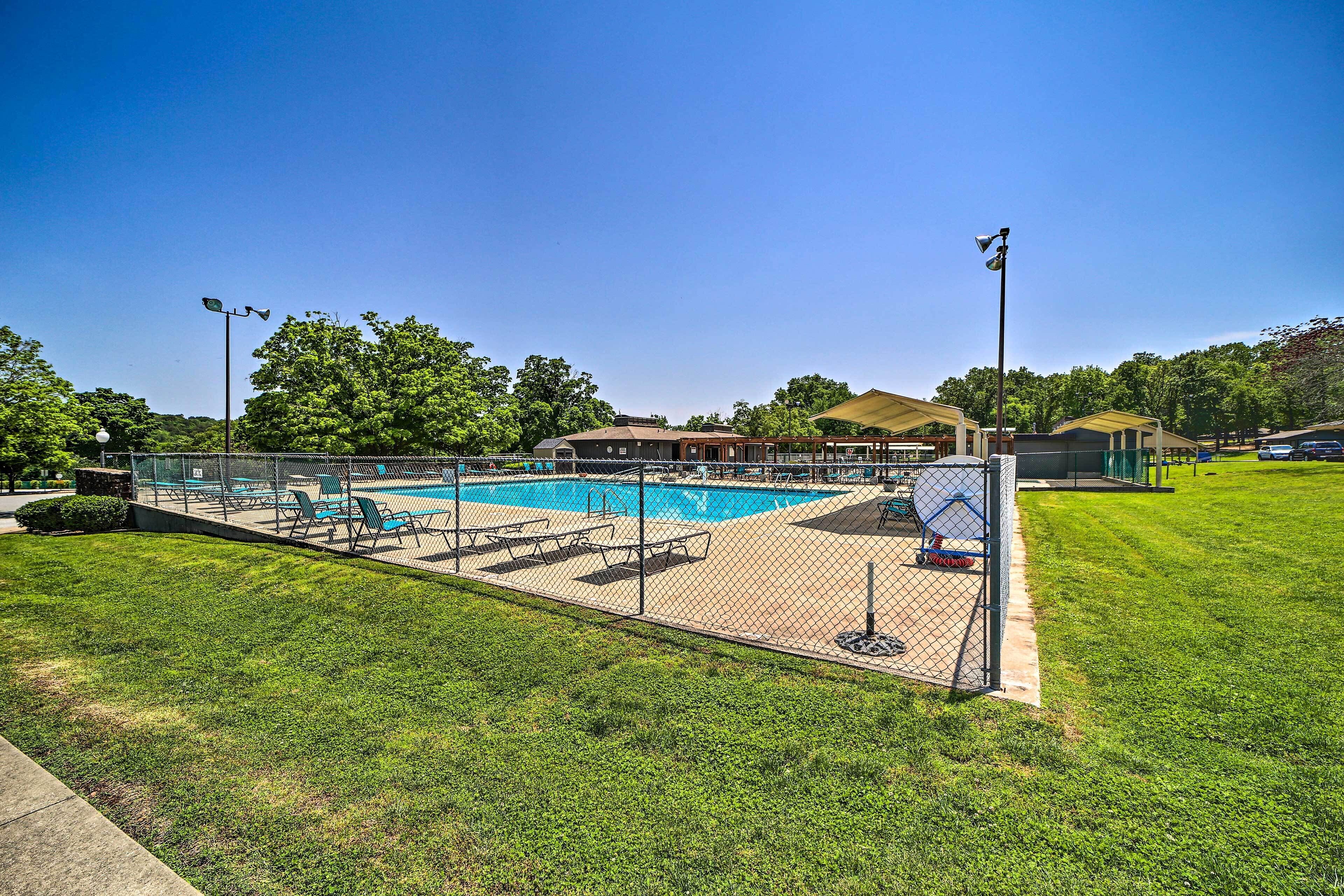 A fenced outdoor swimming pool with lounge chairs and a covered seating area.