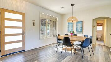 A dining area with a wooden table and chairs, a pendant light, and a view of the outside.